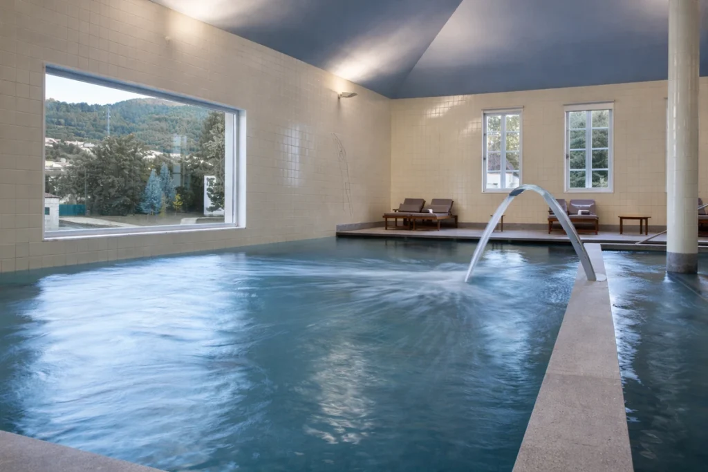 Indoor thermal pool with hydrotherapy fountain at Pedras Salgadas Spa & Nature Park