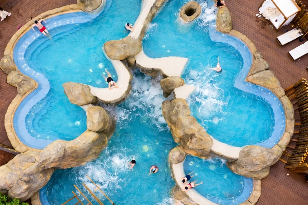 Aerial view of outdoor thermal pools with rock features and hydrotherapy areas