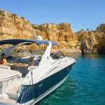 Private luxury yacht with a couple dining beside golden Algarve cliffs and turquoise water.